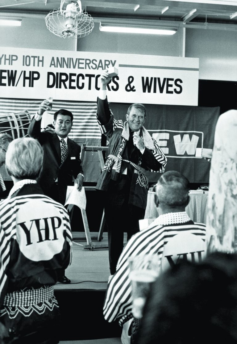 Bill Hewlett raising a sake box while on stage during his visit to Japan to celebrate the 10th Anniversary.