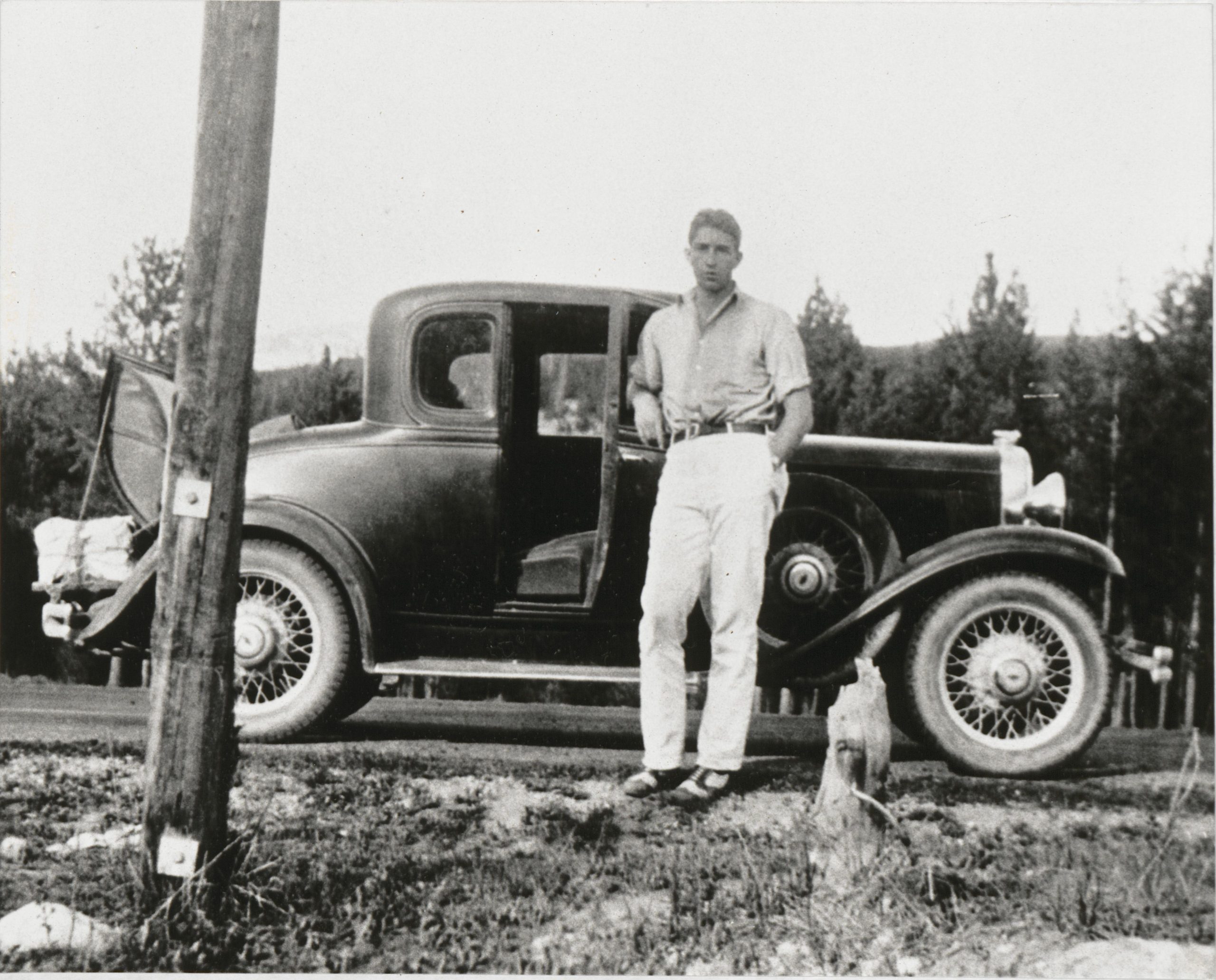 Dave Packard as a young man posing beside a car.