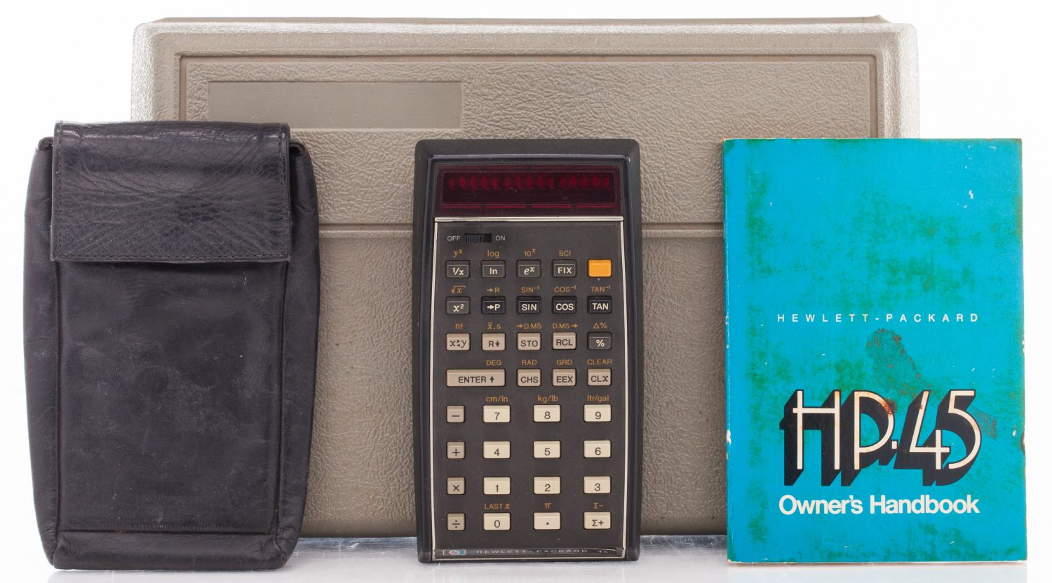 HP 45 calculator with carrying pouch and owner's handbook in front of a plastic storage case.