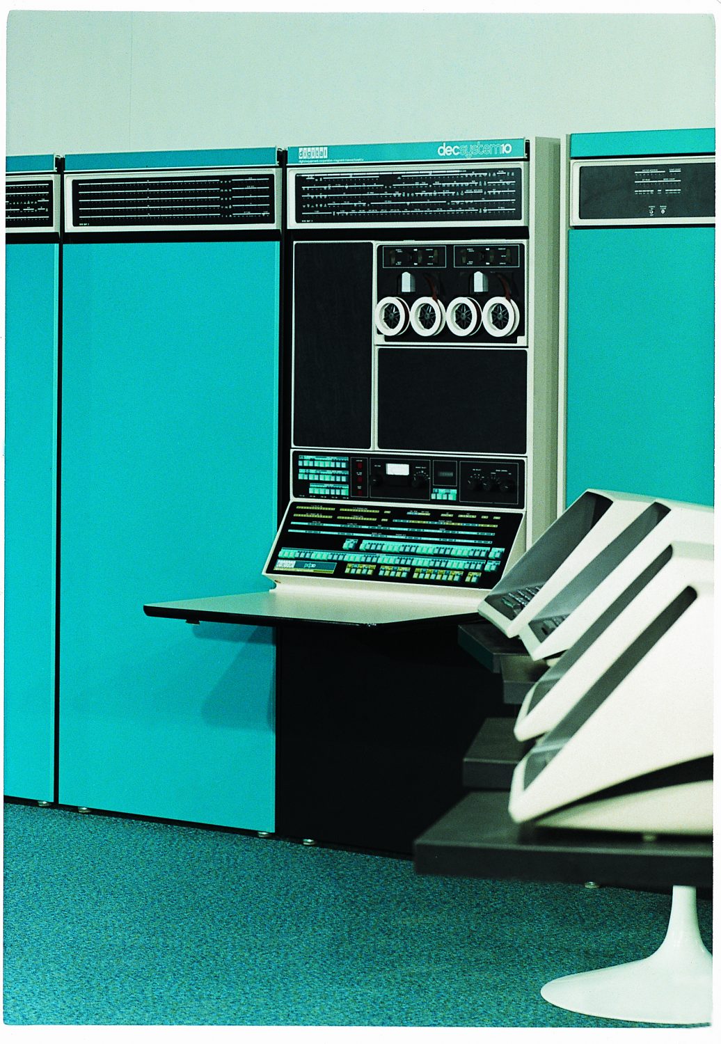 Photo of Digital Equipment Corporation's PDP-10 featuring large teal units and several terminals.