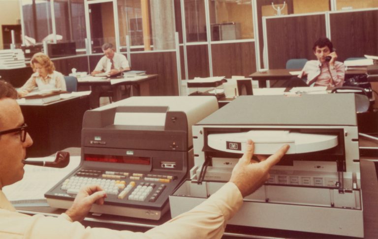 A man in an office works on the HP 9830A programmable calculator, considered by some to be HP's first desktop PC.