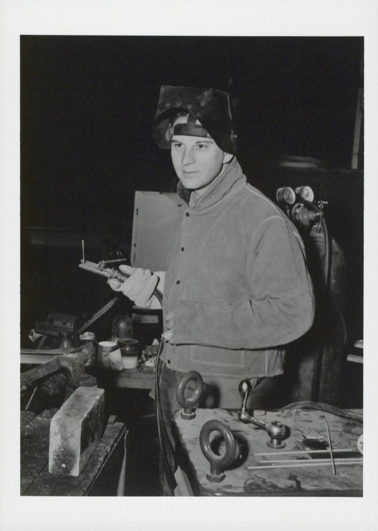 Photo of Harvey Zieber, Hewlett-Packard's first employee, with a welding helmet and blow torch.