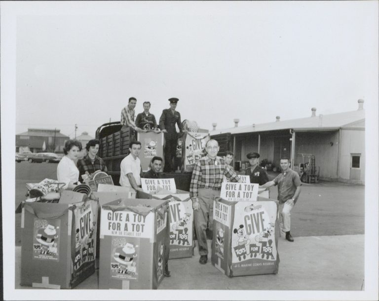 Photo of several HP employees and soldiers with several large boxes filled with toys taken in 1959.