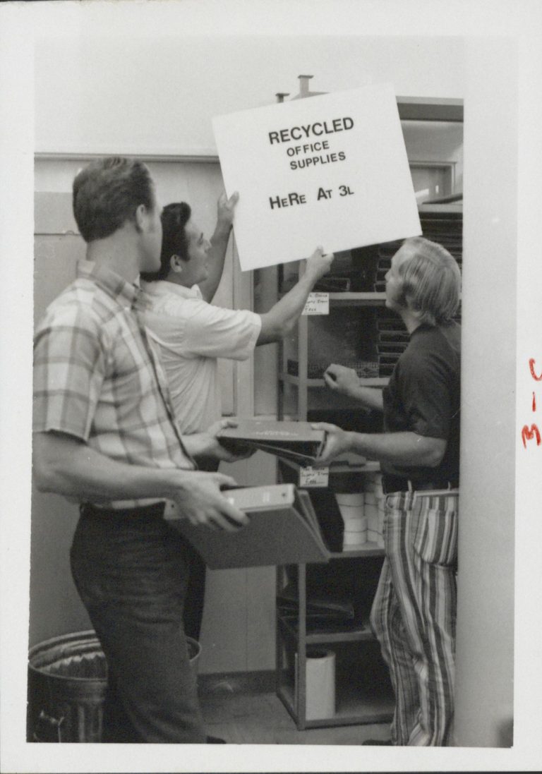 A photo of recycling efforts at HP in 1971. A man holds a sign that reads Recycled Office Supplies Here at 3L.