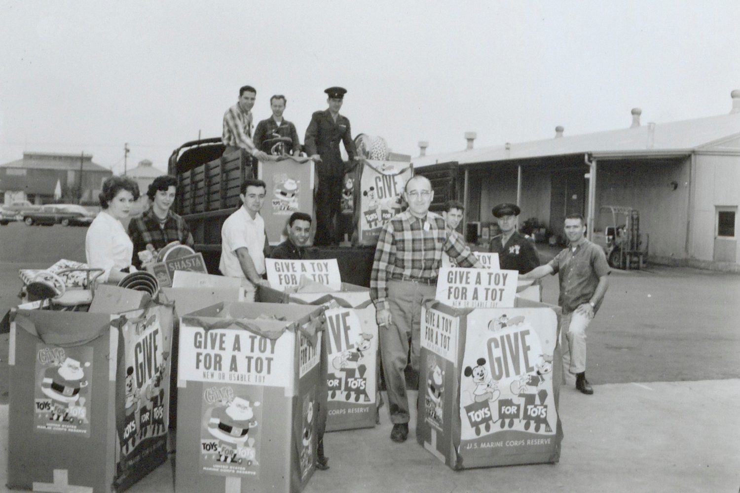 Photo of several HP employees and soldiers with several large boxes filled with toys taken in 1959.