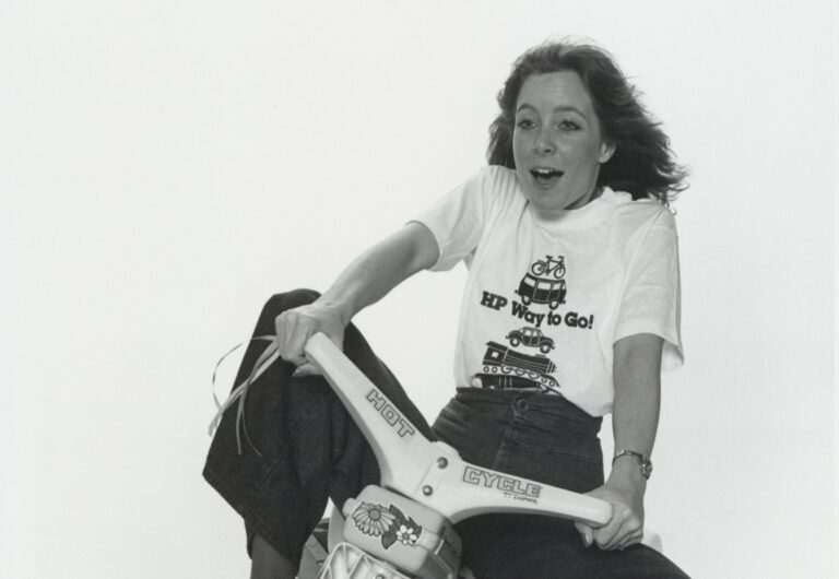 A woman riding a child's tricycle to celebrate Commuting Alternatives Day in 1980.