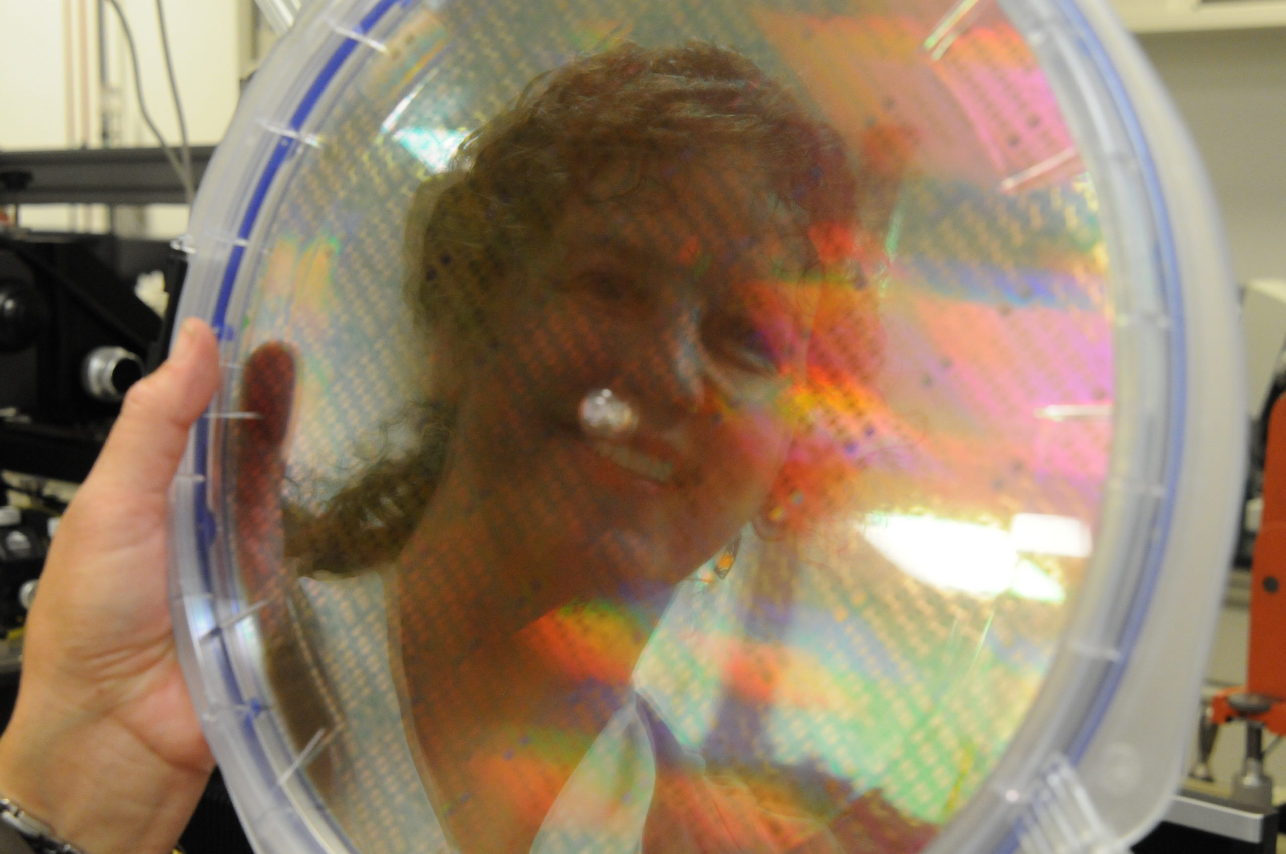 A woman's reflection in a wafer of silicon chips featuring HP memristor technology. 