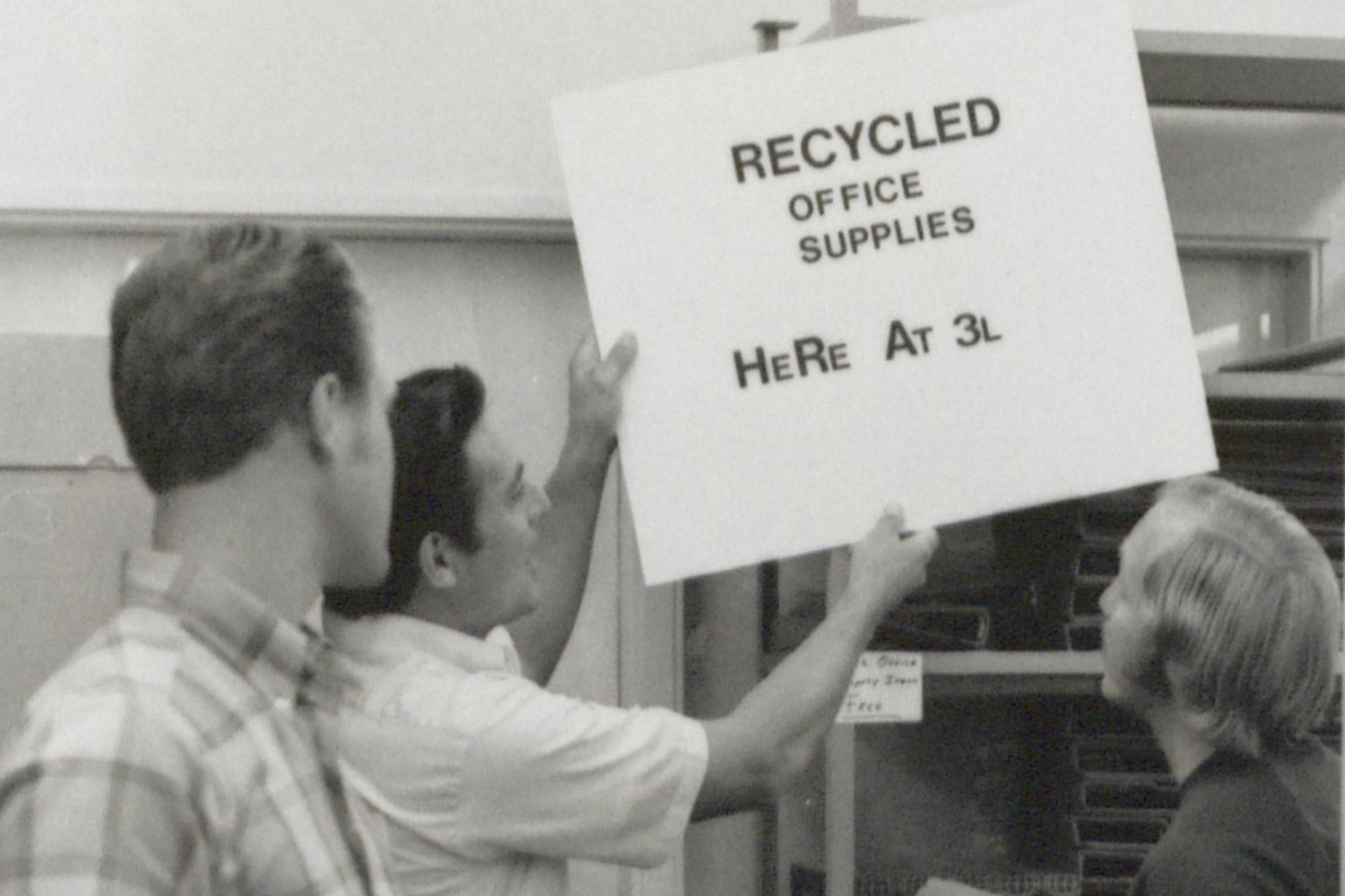 A photo of recycling efforts at HP in 1971. A man holds a sign that reads Recycled Office Supplies Here at 3L.