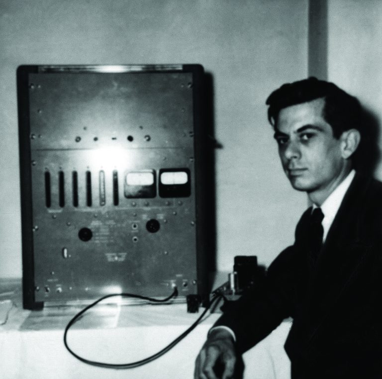 A man poses in front of the Hewlett-Packard 524A radio frequency counter.