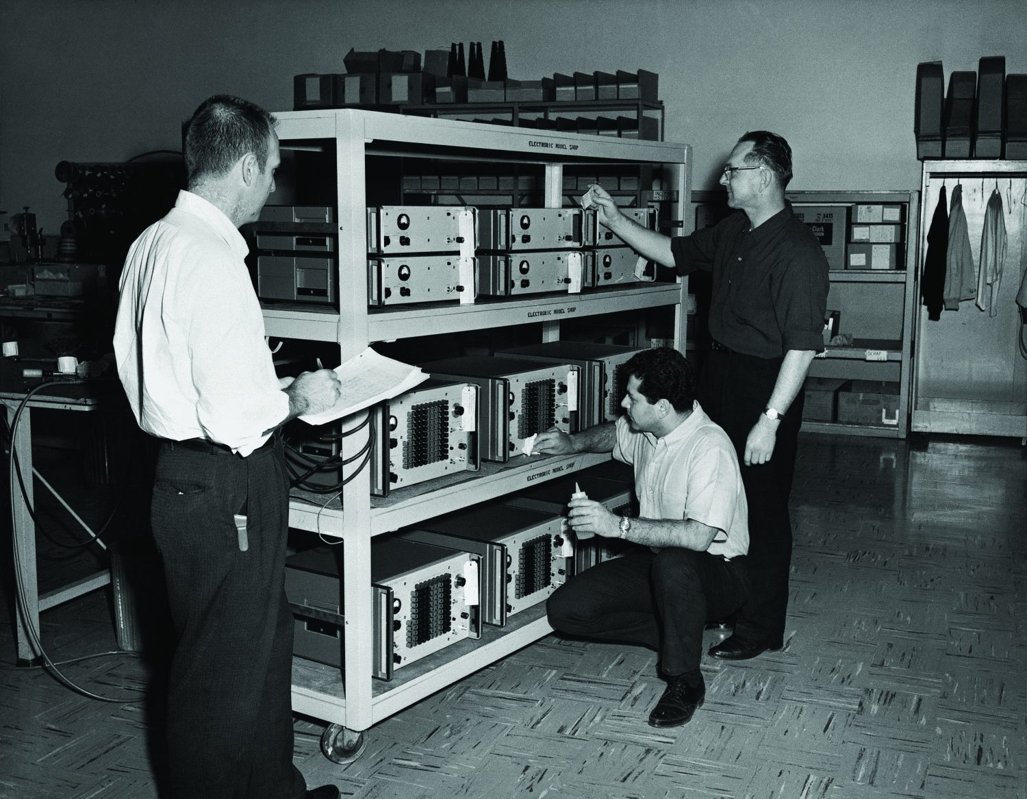 An HP team reviewing shelves of 5100A synthesizer components.