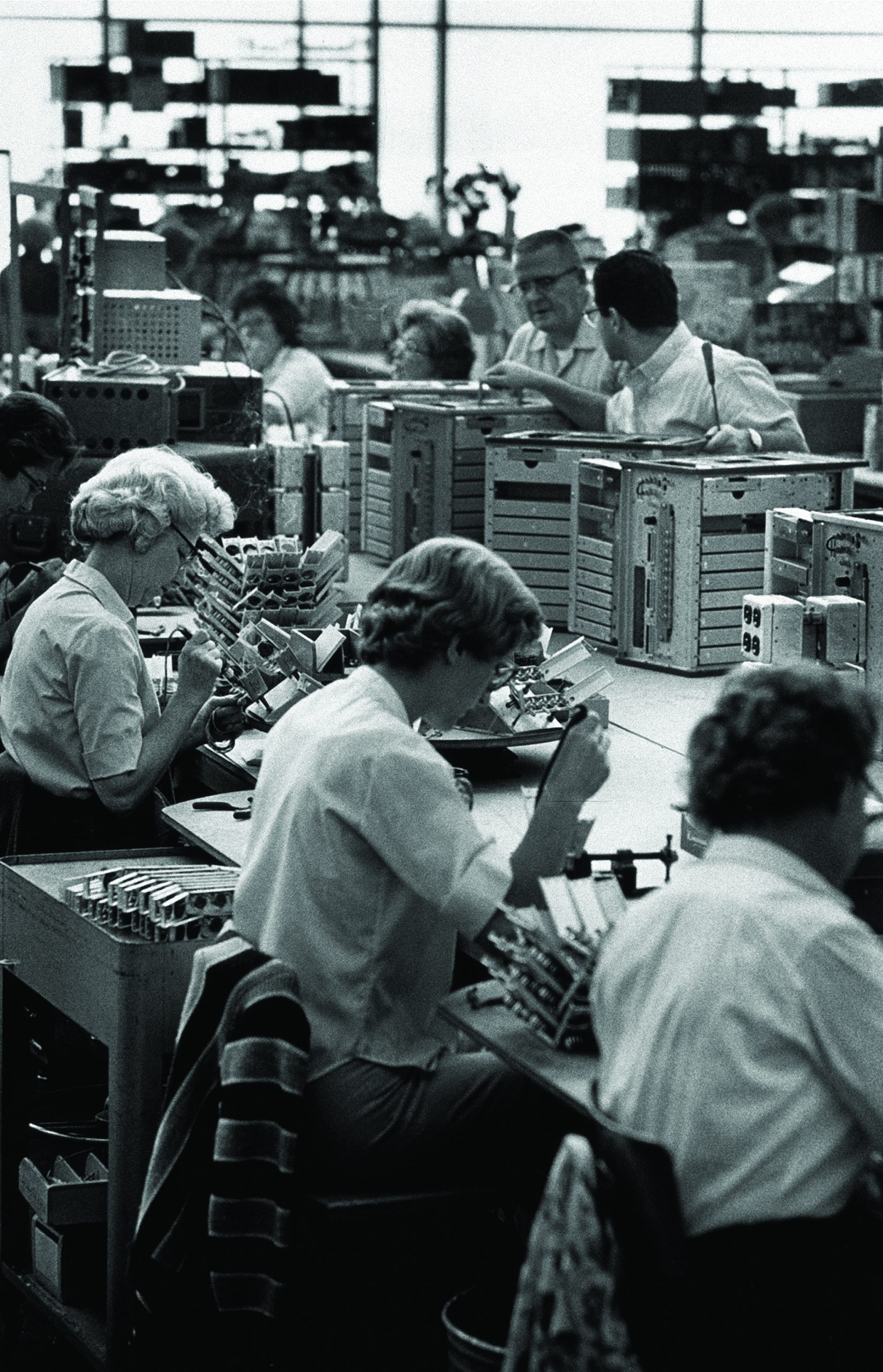 HP employees in a production facility with three women soldering in the foreground.
