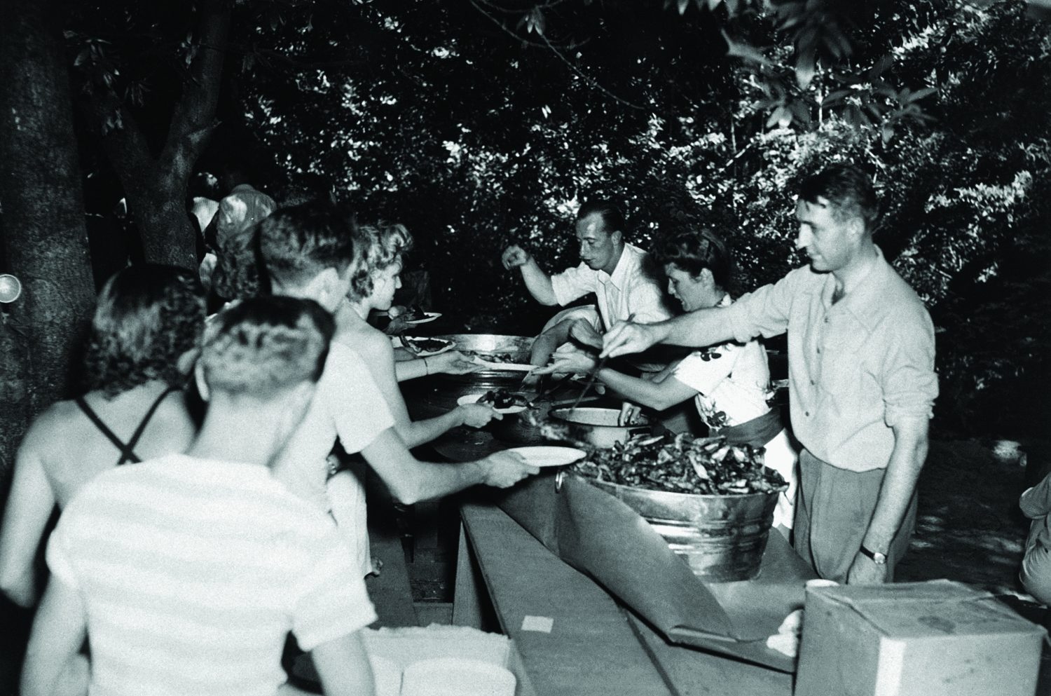 Dave Packard, Lucile Packard and Dick Arms serve a line of HP employees at the 1945 company picnic.