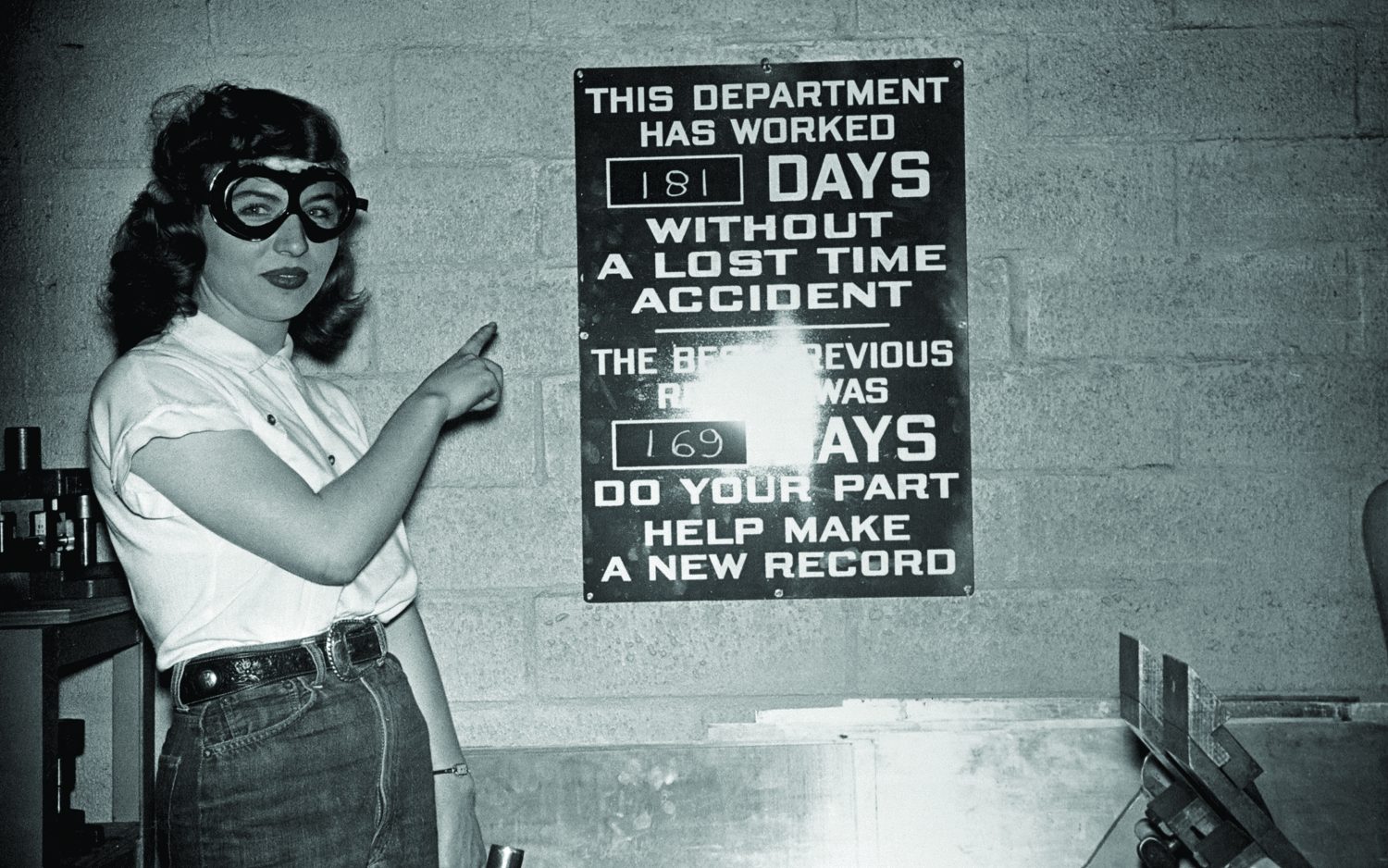 Woman points at a sign showing 181 days without a lost time accident.