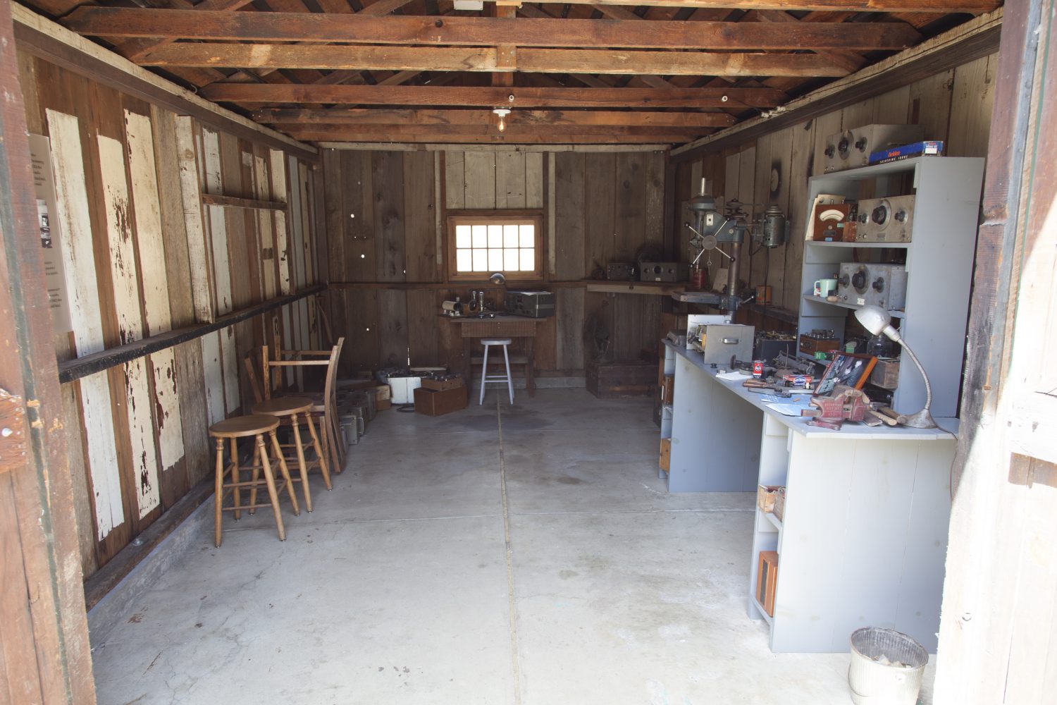 Interior photo of the restored garage on Addison Avenue featuring workbench, drill press and desk.