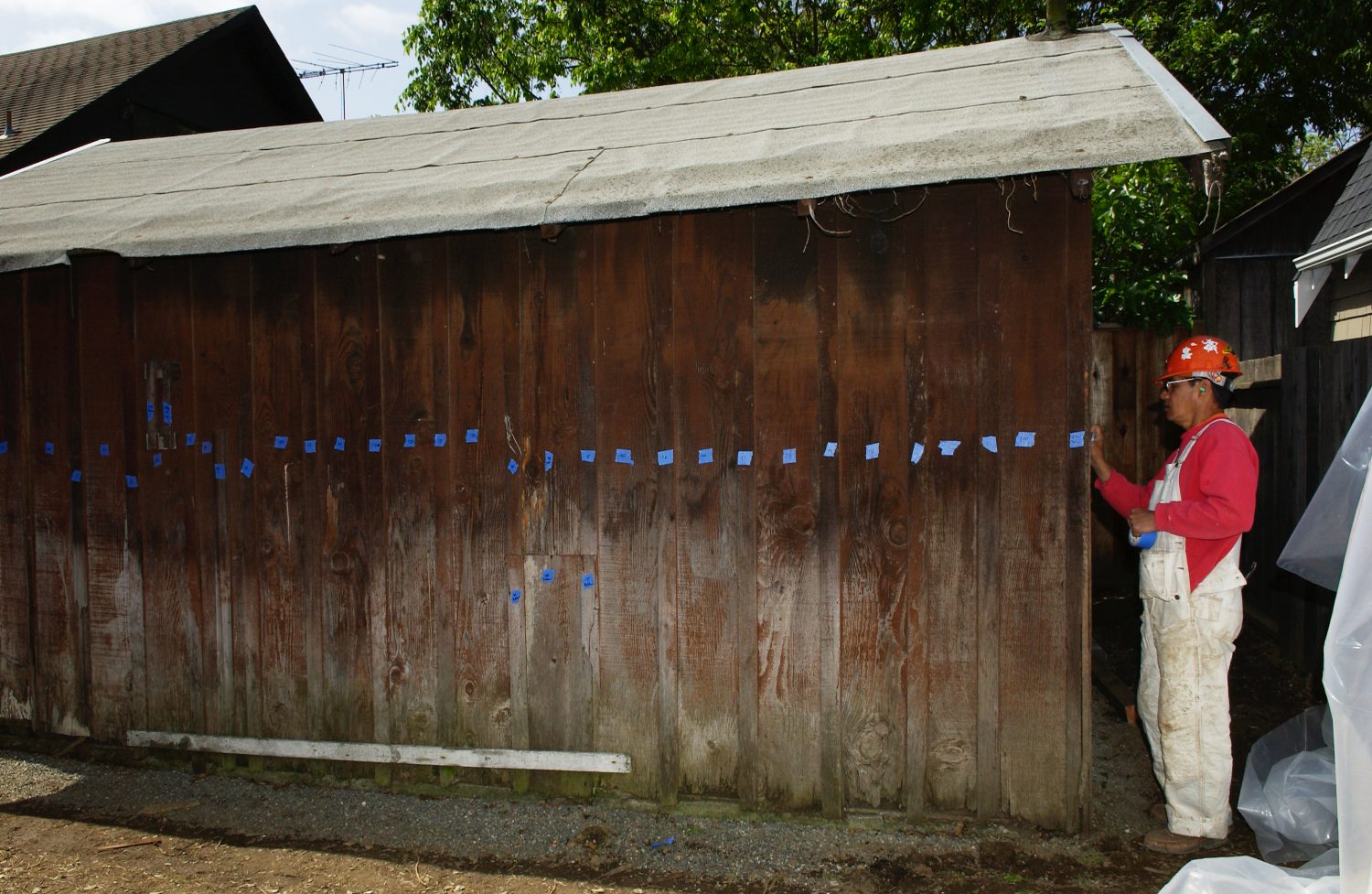 A worker labeling the boards of the garage with blue tape during the Addison Avenue restoration.