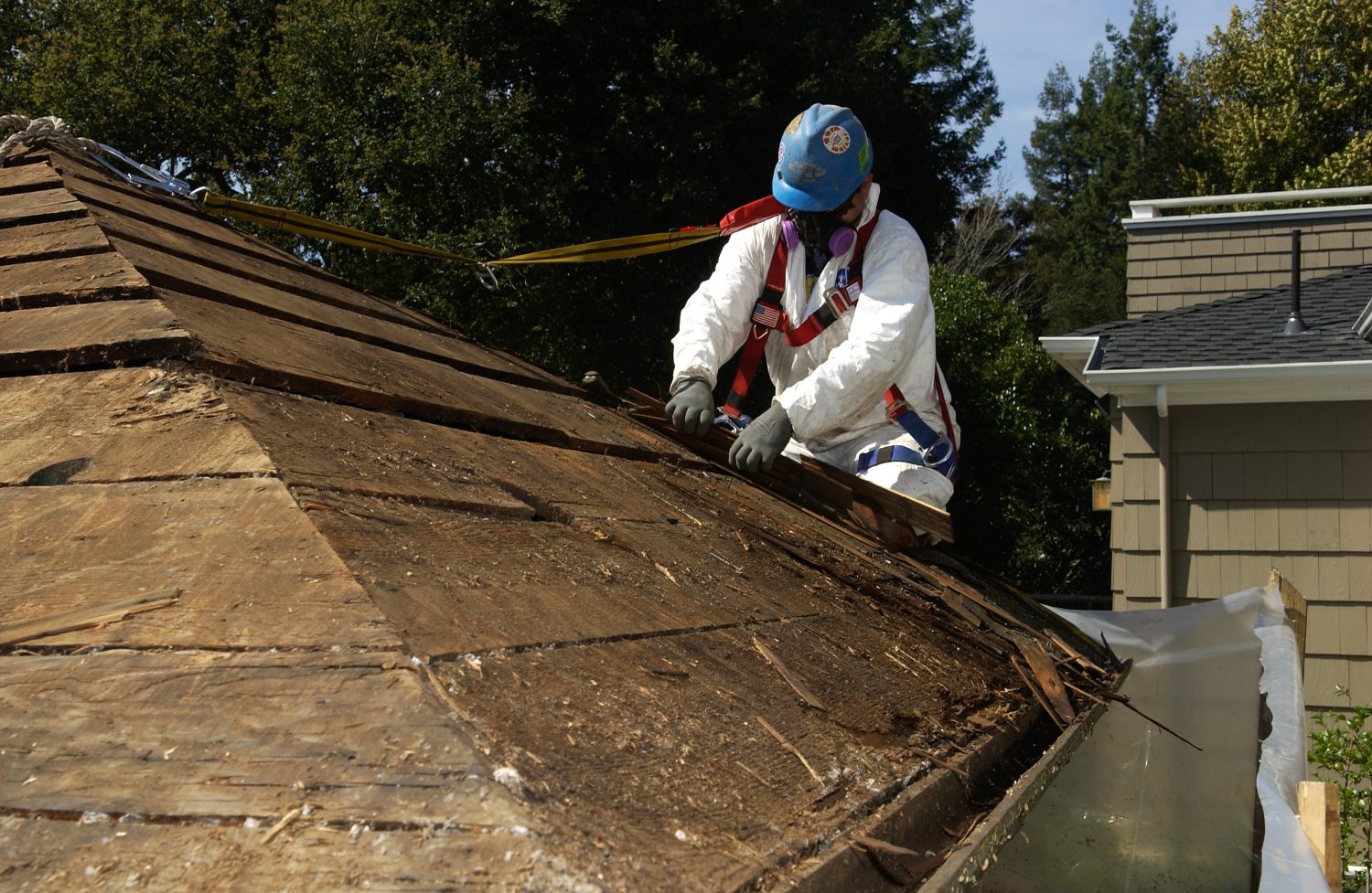 A worker peels away the decaying shingles from the roof of Bill Hewlett's shed on Addison Avenue.