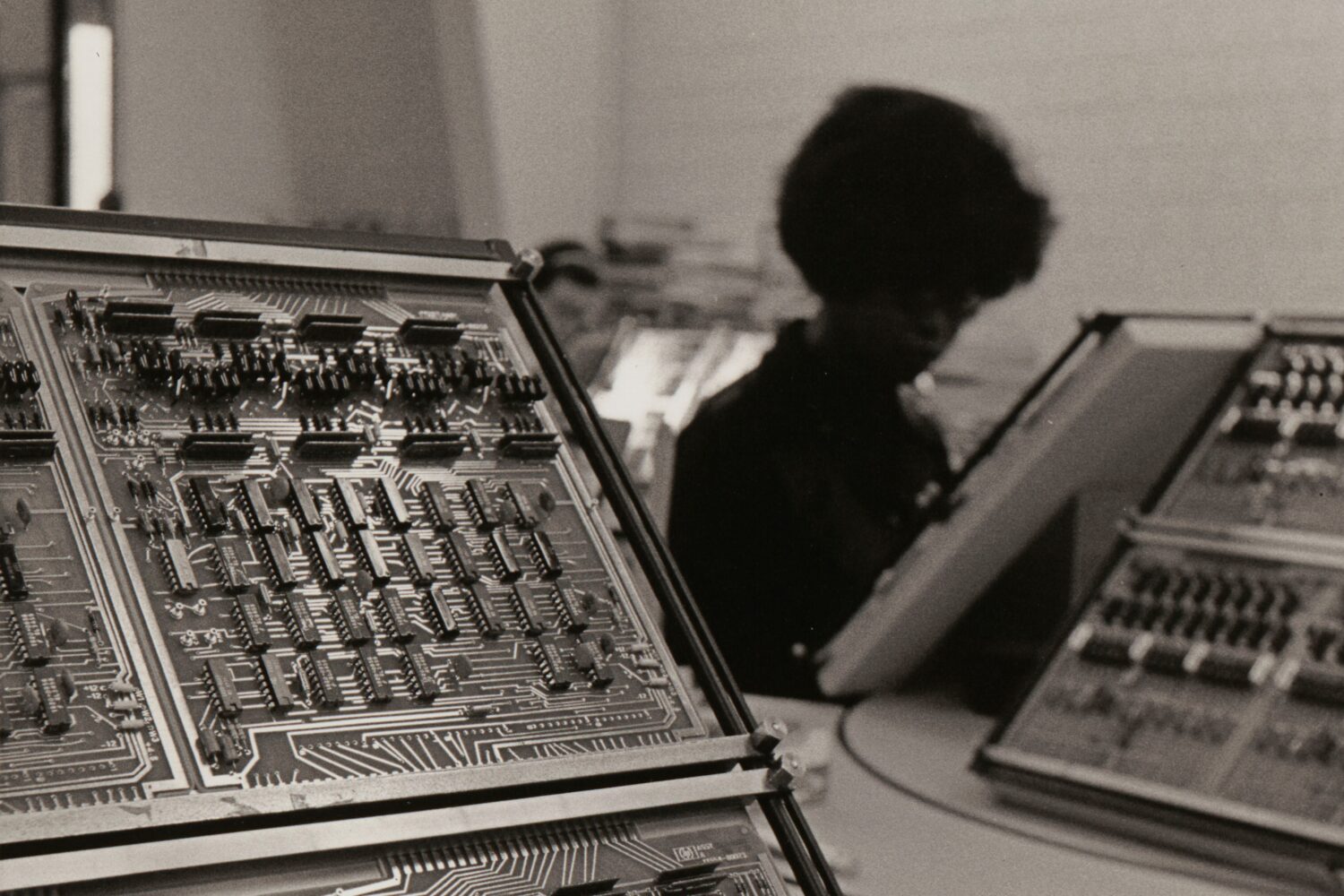 A photo of two computer circuit boards in the foreground and HP employee working in the background.