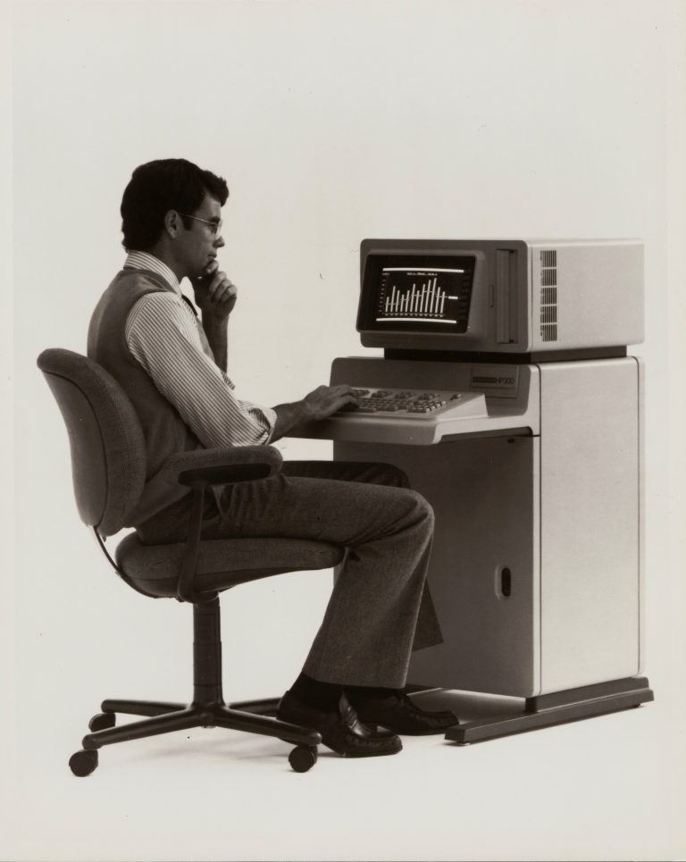 A man sitting at the HP 300 terminal with built-in desk and keyboard.