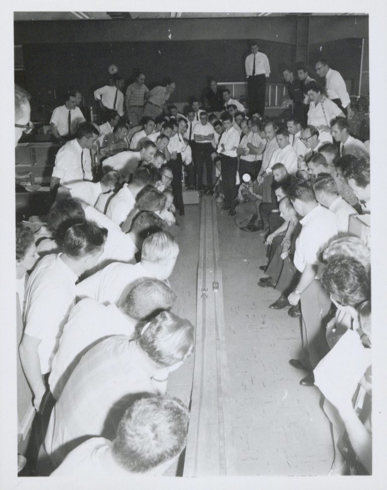 A group of HP Frequency & Time Division employees cheering on as miniature cars go down a track.