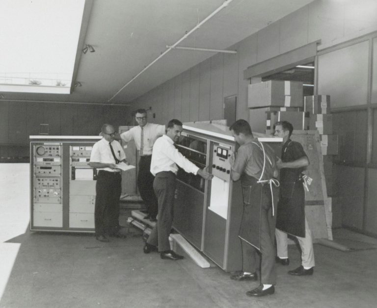 Employees moving the HP 8400A microwave spectrometer in 1964.