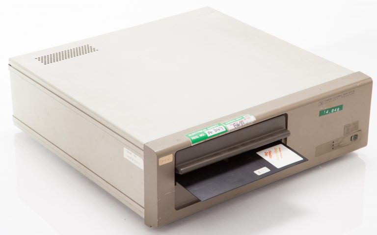 Photo of the HP 9855M floppy disk drive with an 8-inch disk partially in the drive.