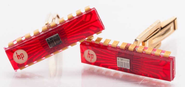 Two gold HP cufflinks with red chips and company objectives printed on a tiny chip in the center of each one.