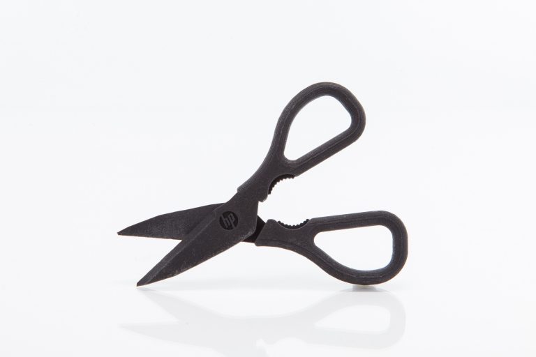 A pair of 3D-printed scissors with the HP logo on the blade.