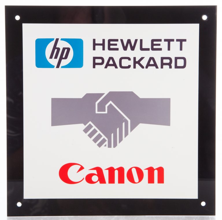 A plaque with the Hewlett-Packard logo on top, Canon logo below and shaking hands between the two.