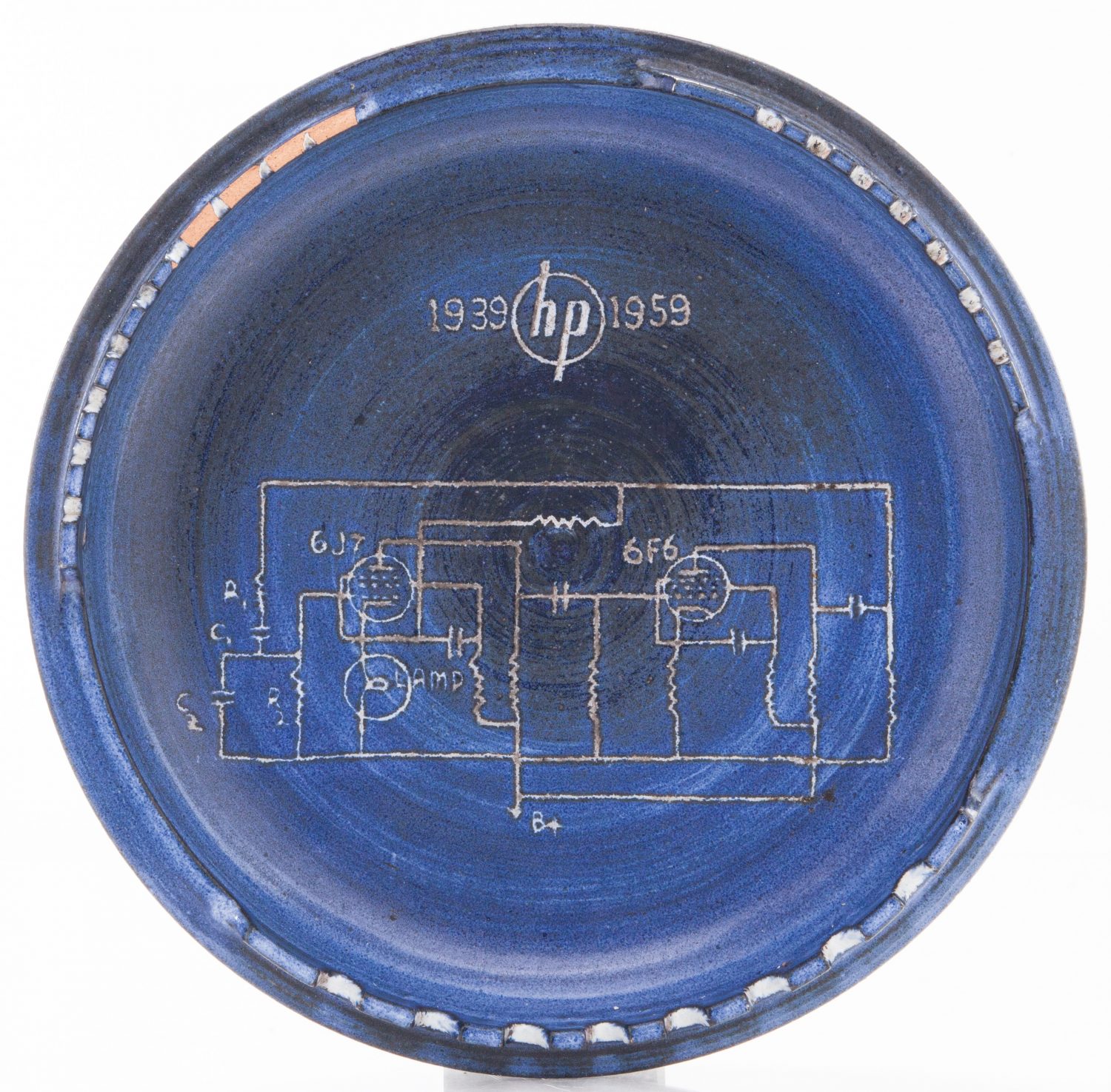 Top-down view of a blue ashtray with the 200A schematic etched in its center. 