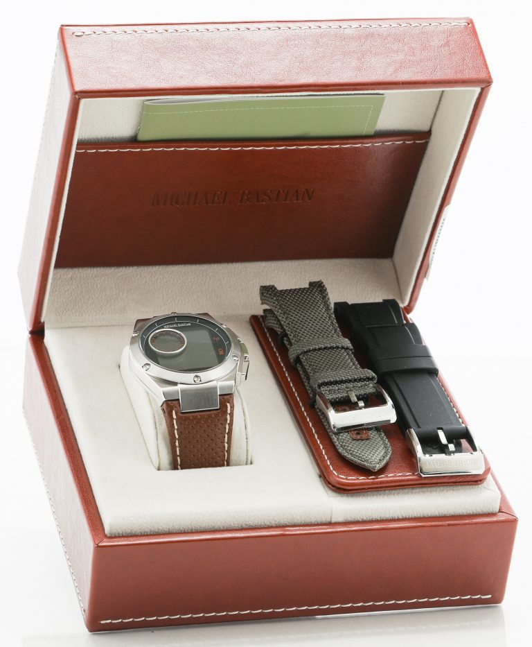 The Michael Bastian smartwatch in its box (opened) with additional strap options.