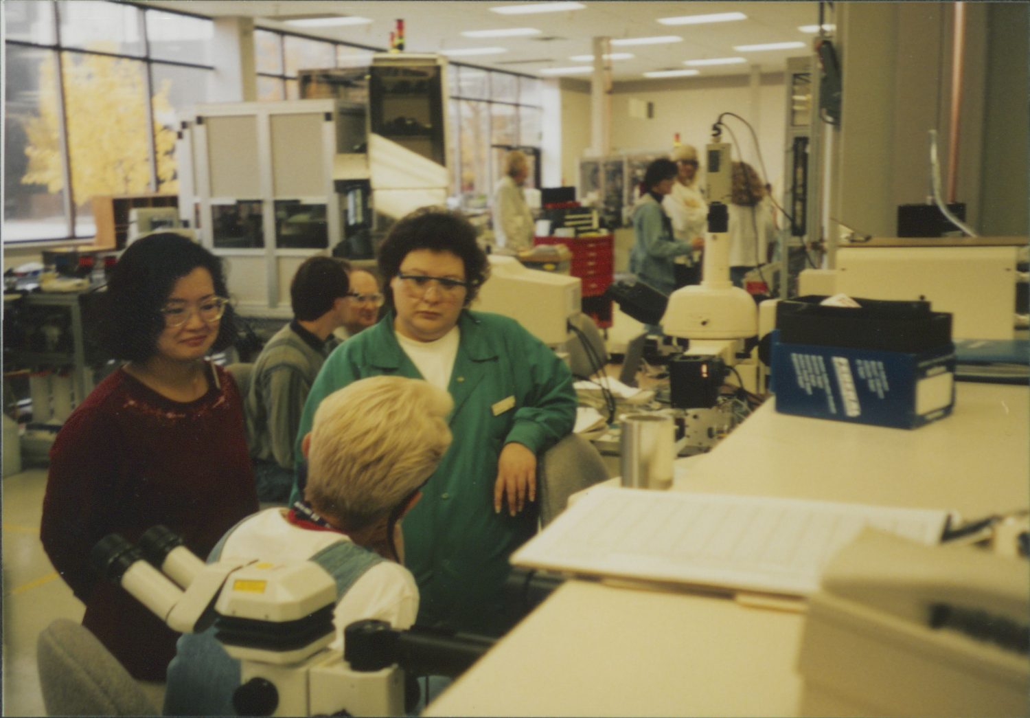 Three women talking at the HP facilities in Boise, Idaho, with other employees in the background.