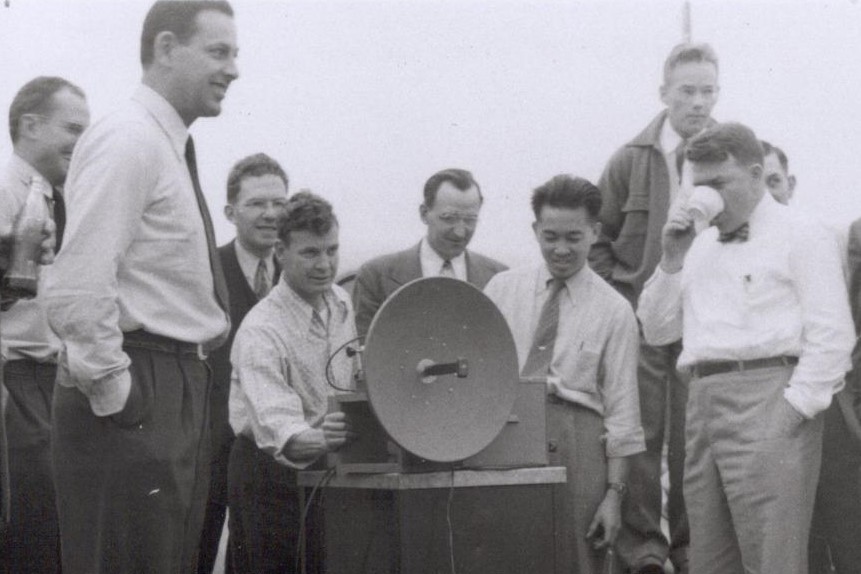 Photo of a microwave signal generator with a crowd gathered around during a demonstration in 1947.