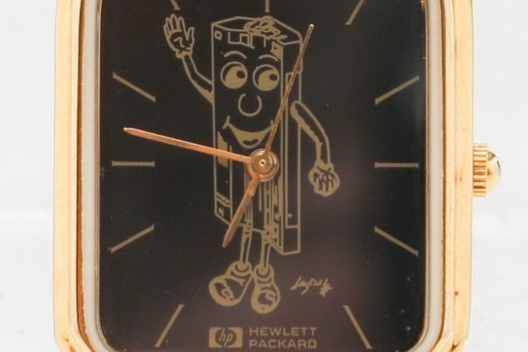 A Hewlett-Packard branded wristwatch featuring an anthropomorphic cartoon caricature of a toner cartridge.