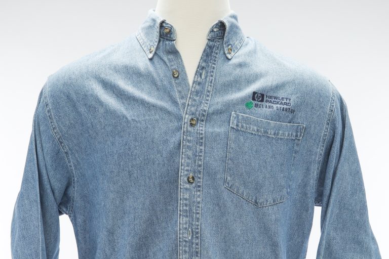 A jean shirt featuring the HP logo and Ireland Startup with a green clover above the pocket.