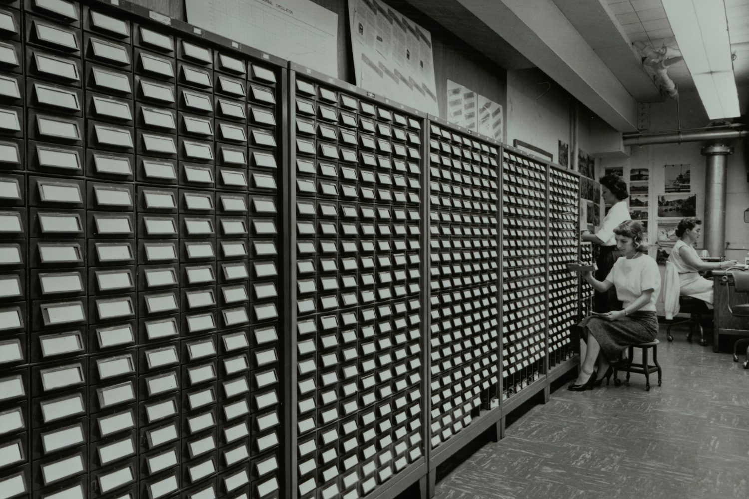 Three women working the name bank card catalog. 