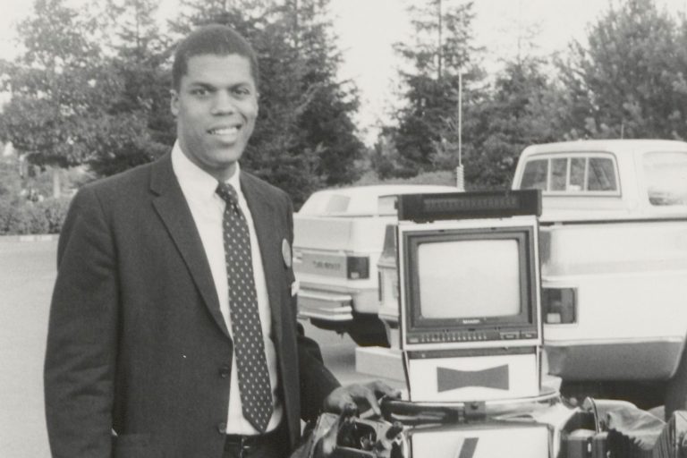 An HP employee poses next to a robot featuring the HP logo on its chest and a monitor for a head.