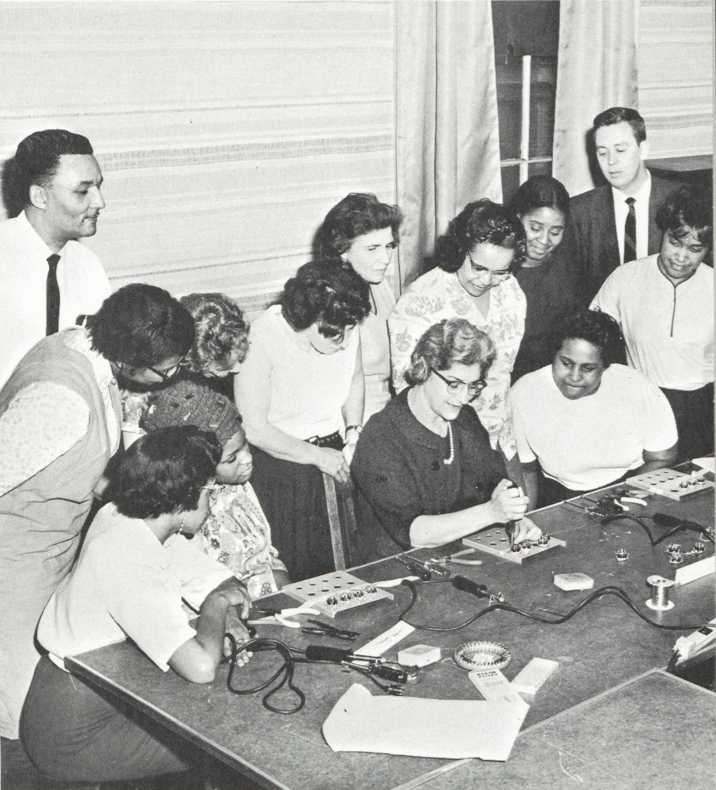 Sanborn plant employees teaching assembly techniques to a group of women at the Cambridge Community Center.