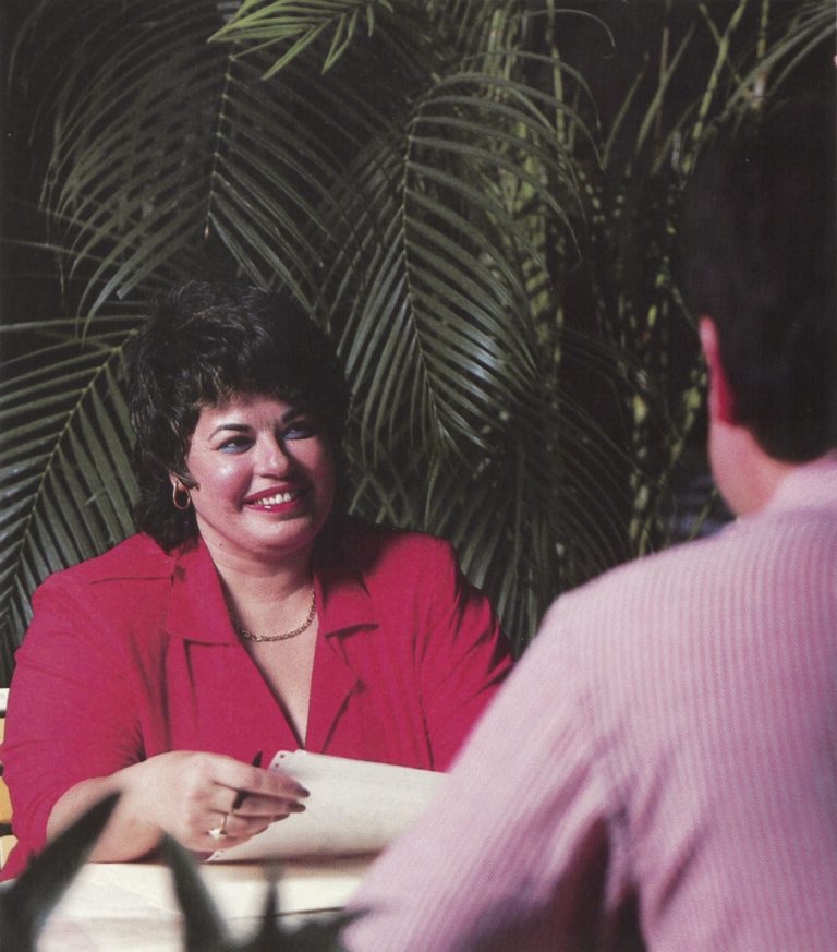 Mabel Esteves seated at a desk opposite a male colleague in 1988.